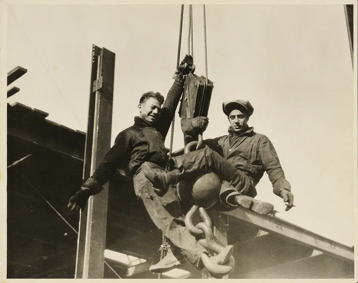Young structural steel workers high on the open frame of a skyscraper under construction.