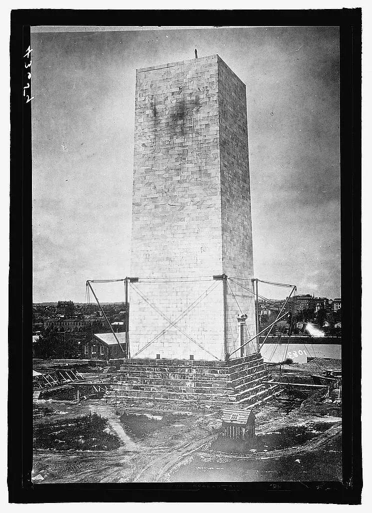 The unfinished marble shaft of the Washington Monument braced in rigging, around 1879.