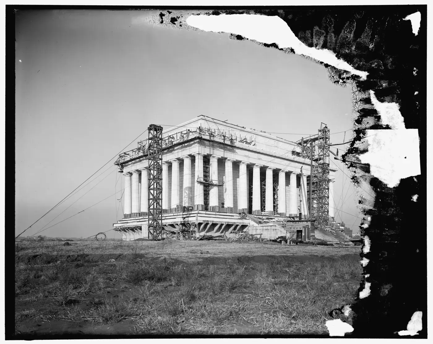 The Lincoln Memorial's marble colonnade rising under timber derricks and scaffolding during construction.