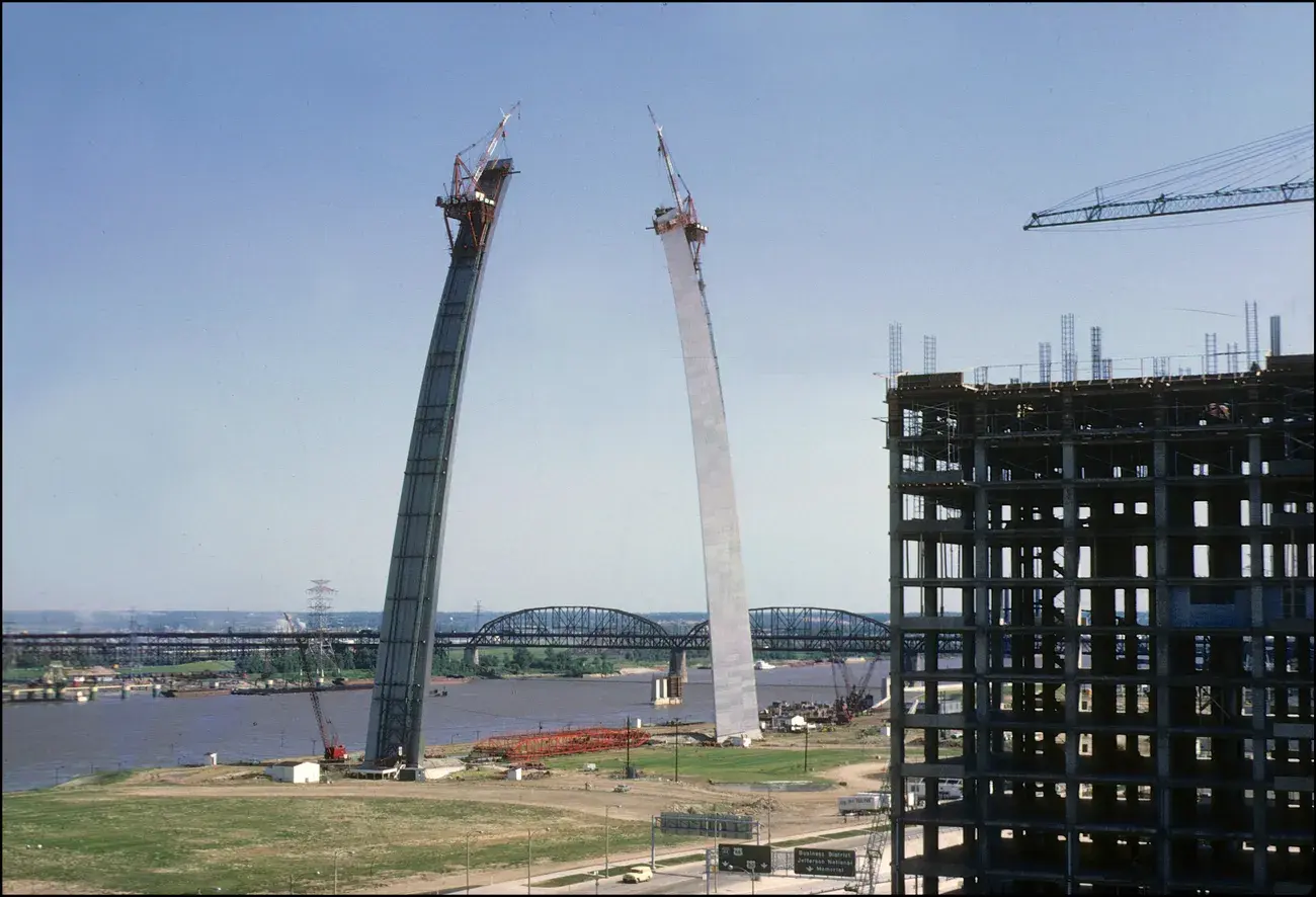 The two stainless-steel legs of the Gateway Arch rise with creeper derricks before the keystone joined them, 1965.